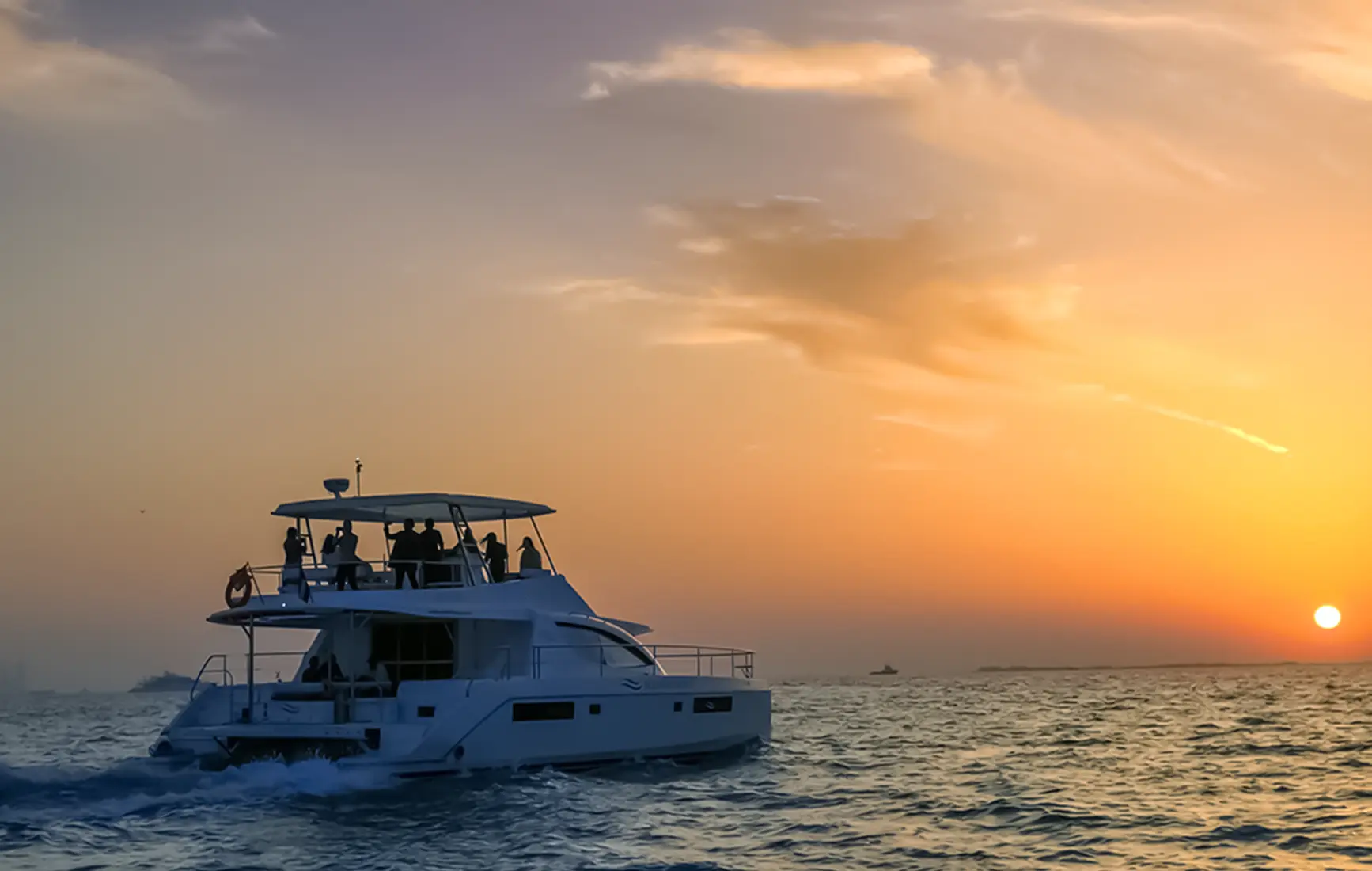 A yacht cruising off the coast at sunset